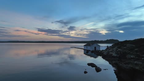 reflections of sunset in fornells bay, menorca with boat house and pier on the lake