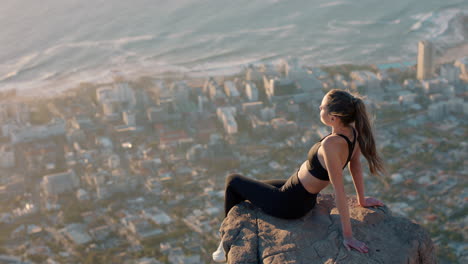 healthy woman on mountain top looking at calm view of ocean at sunset girl sitting on edge of cliff enjoying freedom contemplating journey