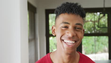 Portrait-of-happy-african-american-male-teenage-boy-at-home,-slow-motion