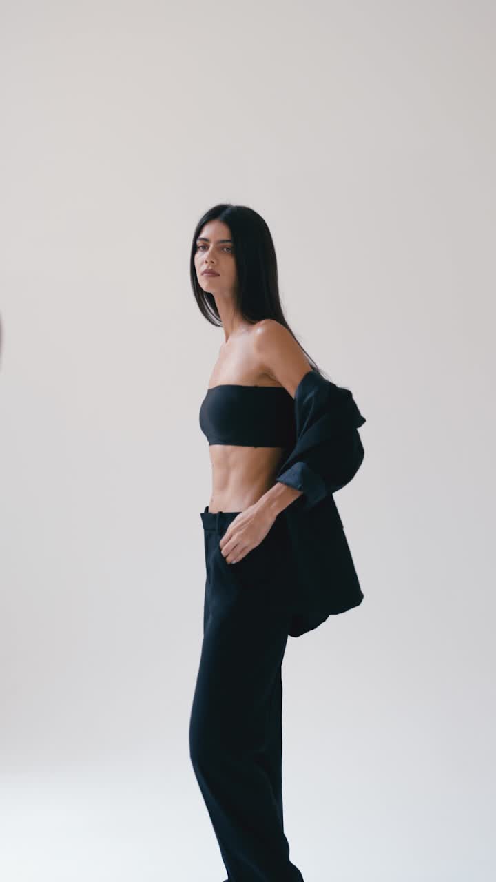 Elegant woman in black suit posing in studio