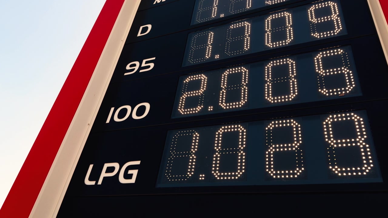 Avrupa'da bir akaryakıt istasyonunda gündüz çekilmiş, dizel, benzin ve LPG fiyatlarını gösteren, aydınlatılmış dijital yol kenarı tabelasının yakın çekim görüntüsü.