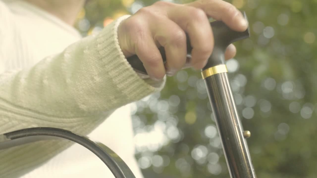 mujer con bastón se sienta en un banco