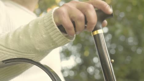 Woman-with-walking-stick-sits-down-on-bench