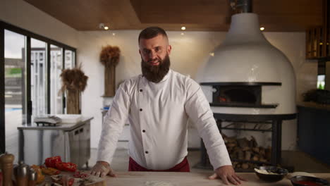 hombre profesional chef culinario de pie mirando la cámara en la cocina del restaurante.
