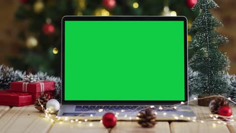 Laptop-with-green-screen-on-screen,-with-christmas-decorations-and-tree