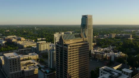 birds eye aerial view of skyscraper buildings in green city at sunrise