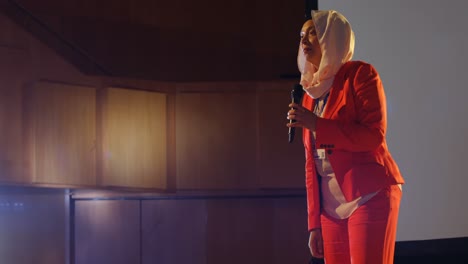 mujer de negocios hablando en el escenario en el auditorio 4k