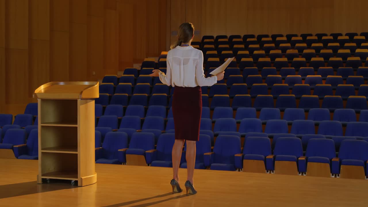 joven mujer de negocios caucásica practicando el discurso en un auditorio vacío 4k