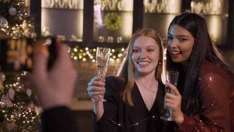 camera focuses on two friends dressed in elegant clothes at a new year's party, a friend takes a picture with a camera