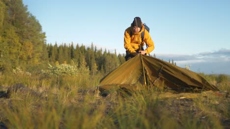 adventurous camper pitching camping tent inserting support poles - ground level orbit tracking slow-motion shot