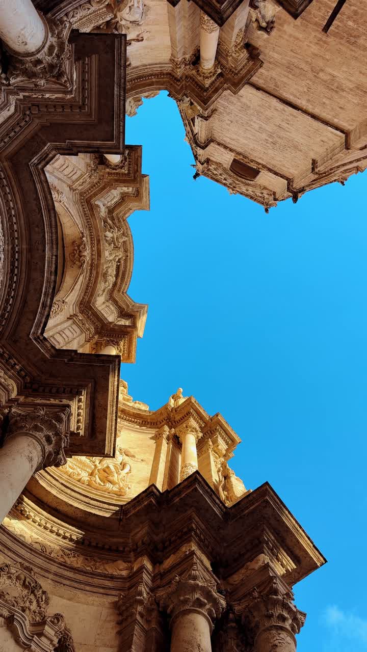 Prospettiva verticale dal basso di dettagli architettonici in pietra di cattedrale. Vista dal basso verso l'alto di elementi architettonici barocchi e sculture su un edificio storico in pietra.