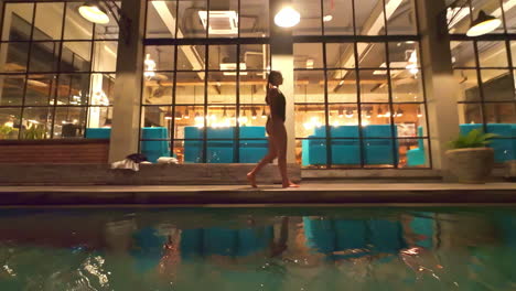 stylish woman in black swimsuit strolling poolside at swarga suites bali berawa