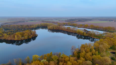 aerial view of a calm dutch lake. golden autumn trees surround a serene lake under a soft blue sky in the netherlands, showcasing the beauty of nature