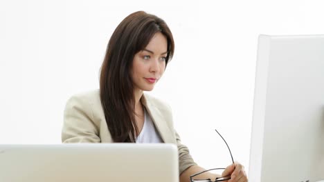 Woman-working-at-her-desk-using-laptop-and-computer