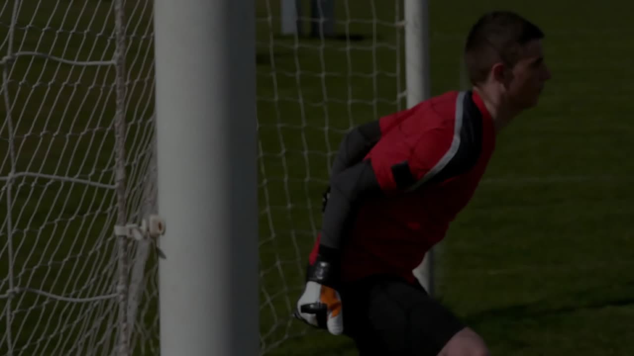 Portiere che risponde a un movimento fuori campo tuffandosi sul campo con linee di analisi sportive sfumate sulla rete