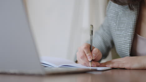 mujer de negocios analizando el gráfico y escribiendo en el portátil. trabajo remoto mujer joven con gafas escribe notas en el portapapeles y escribiendo en el teclado del portátil