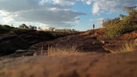 static wide shot of woman standing close to cliff on top and enjoying view over karijini national park in australia