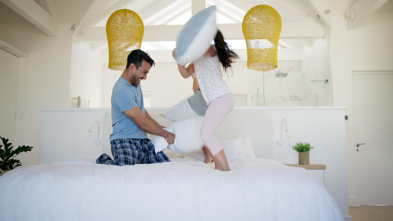 feliz familia pelea de almohadas en el dormitorio