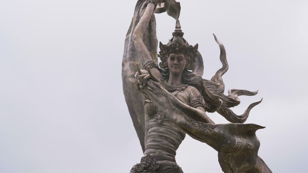 Cinematic footage featuring a smooth sliding-down camera movement along the iconic stone angel statues at Taman Dedari in Ubud, Bali, Indonesia