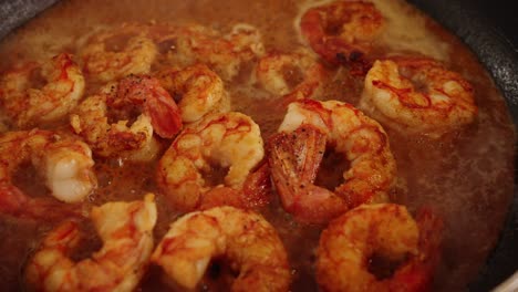 extreme close up shot of simmering broth with delicious shrimps cooking and bubbling gently on the pan with aromatic steams raising in the air