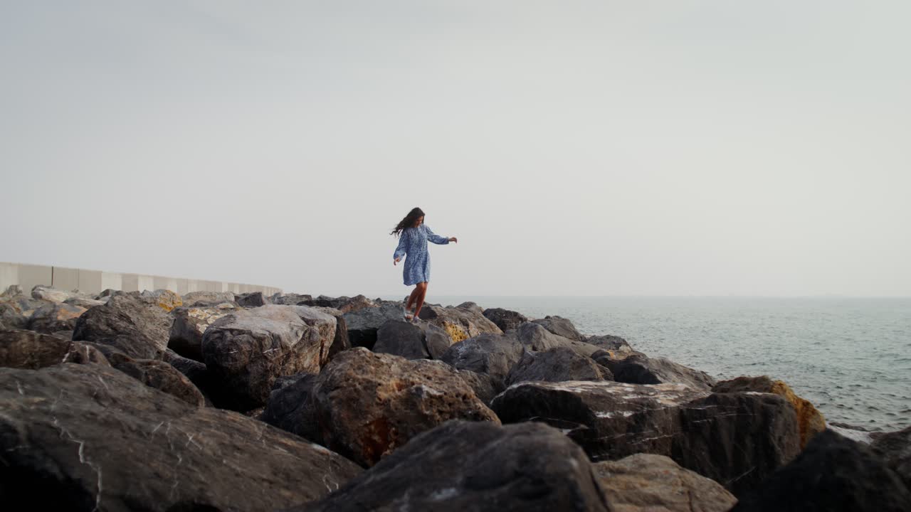 chica de pie en las rocas junto al océano