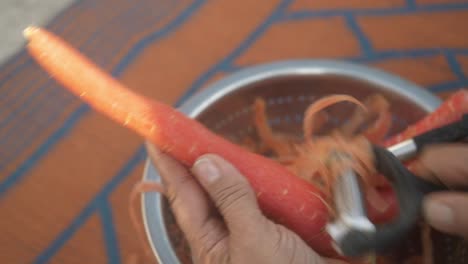 closeup of peeling fresh orange carrot from vegetable peeler