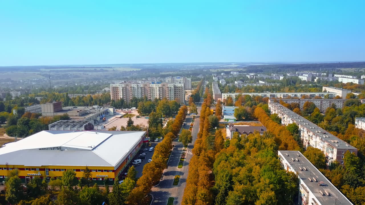 Flying along the road through the provincial city. Aerial view over the multi-storied buildings on sunny day.