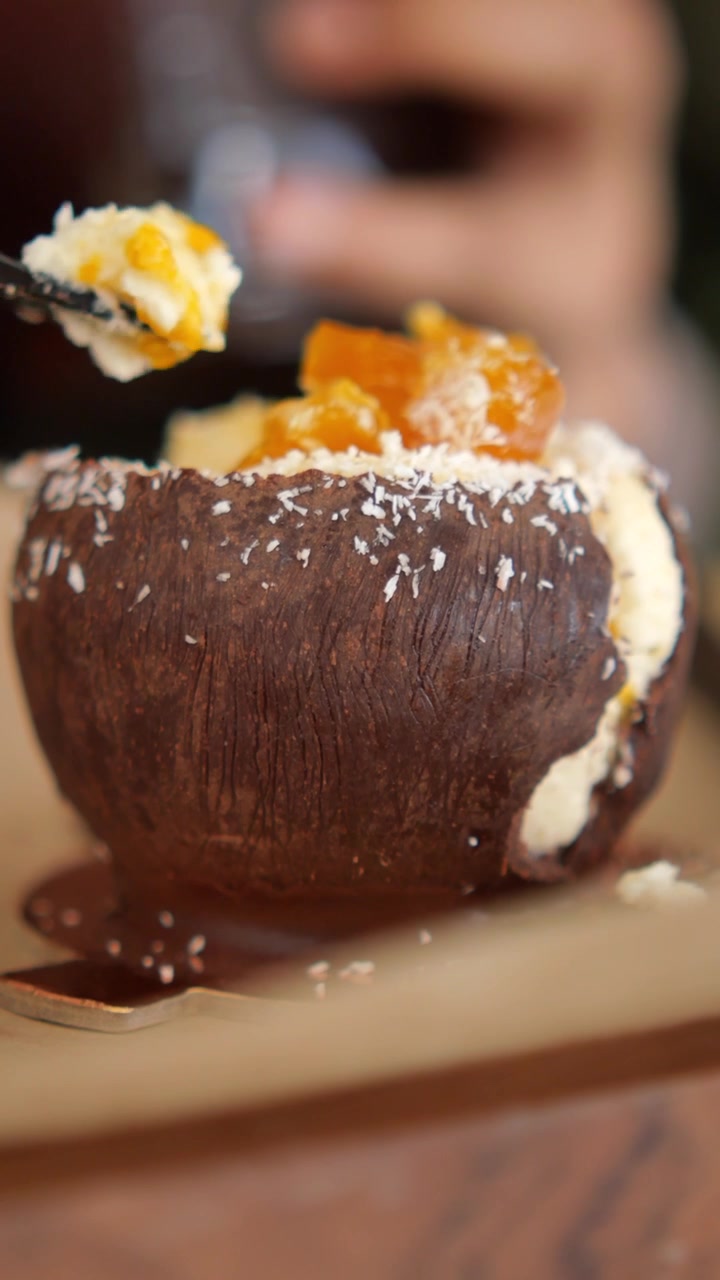 Persona che mangia un dessert cremoso servito in un guscio di cioccolato