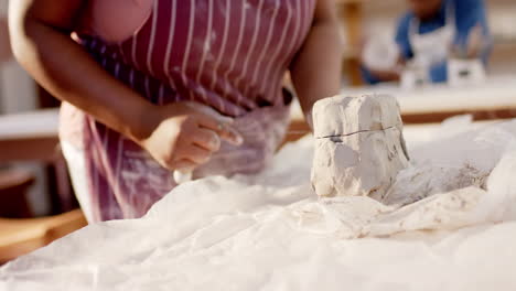 Hands-of-african-american-female-potter-cutting-clay-with-wire-in-pottery-studio,-slow-motion