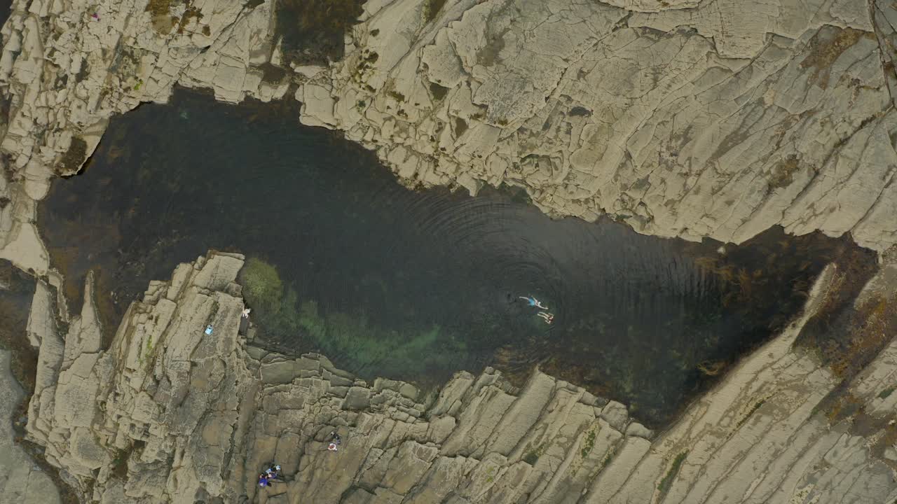 Wide aerial view of a Pollock hole in Kilkee with a couple swimming joyfully