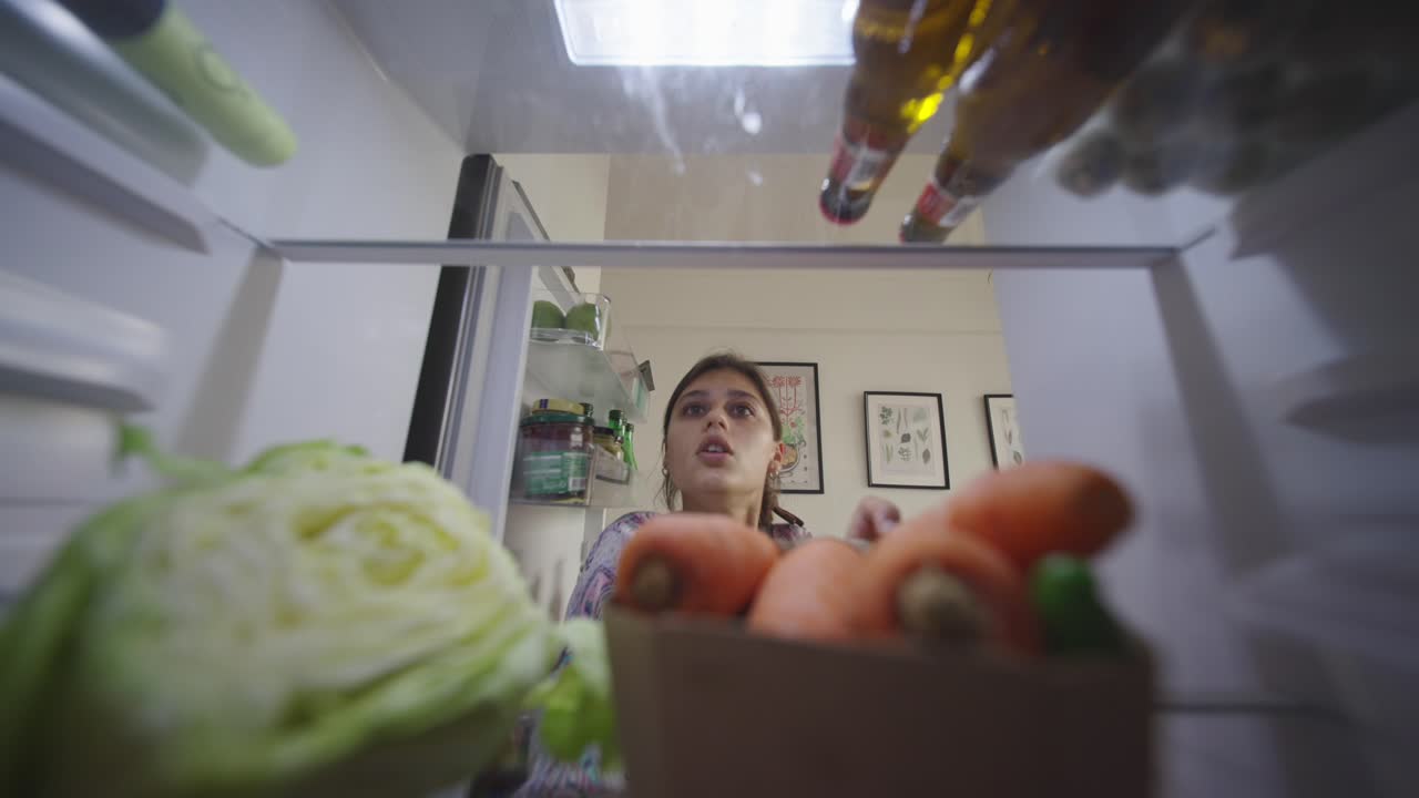 Woman looking inside fridge at night