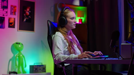 young woman gaming at her desk with a headset and microphone