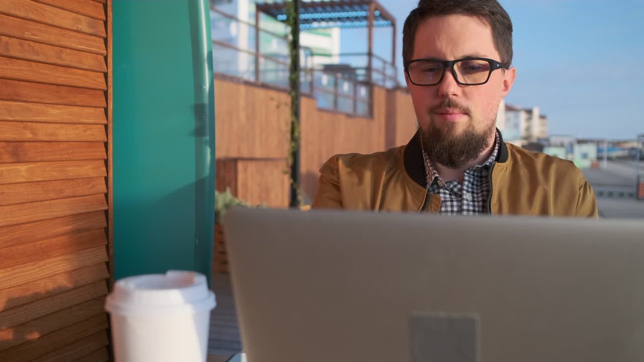 hombre trabajando en una computadora portátil en un café al aire libre