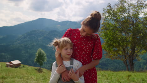 Woman-daughter-standing-mountain-meadow-close-up.-Mom-kissing-blonde-child.