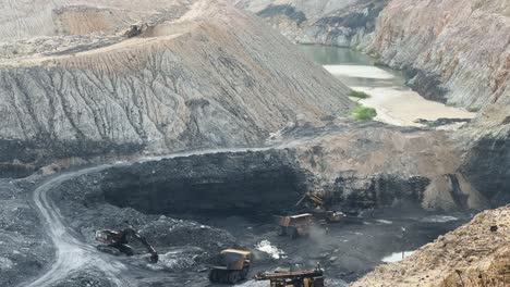 a long shot captures the impressive scale of a mining operation in progress, where a powerful excavator is actively filling a large mining dump truck with coal