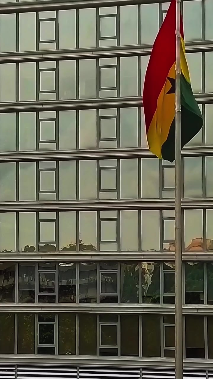 Bandeira de Gana tremulando em frente a um prédio moderno em Accra