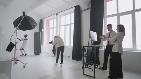 behind-the-scenes photo shoot: a photographer in a photo studio uses a flash for photos of a black professional football player. photo shoot in the studio of a sports magazine advertising