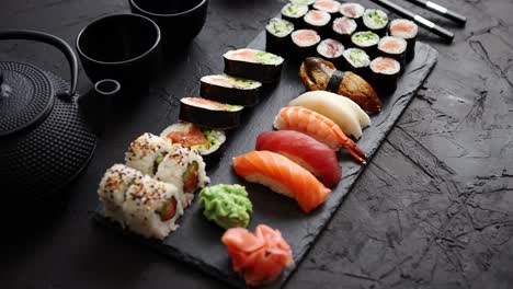 surtido de diferentes tipos de rollos de sushi colocados en tablero de piedra negra