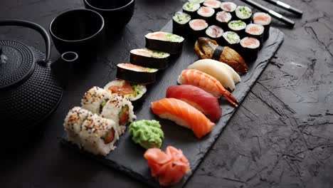 assortment of different kinds of sushi rolls placed on black stone board