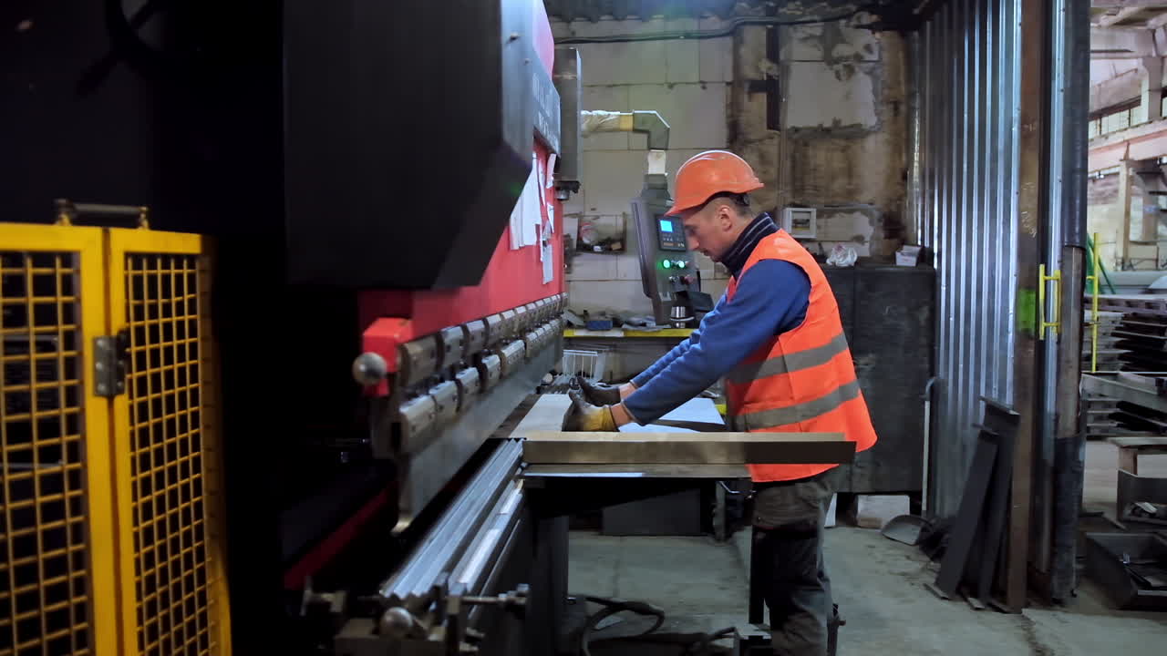 Operator bending metal sheet. Side view of metal processing