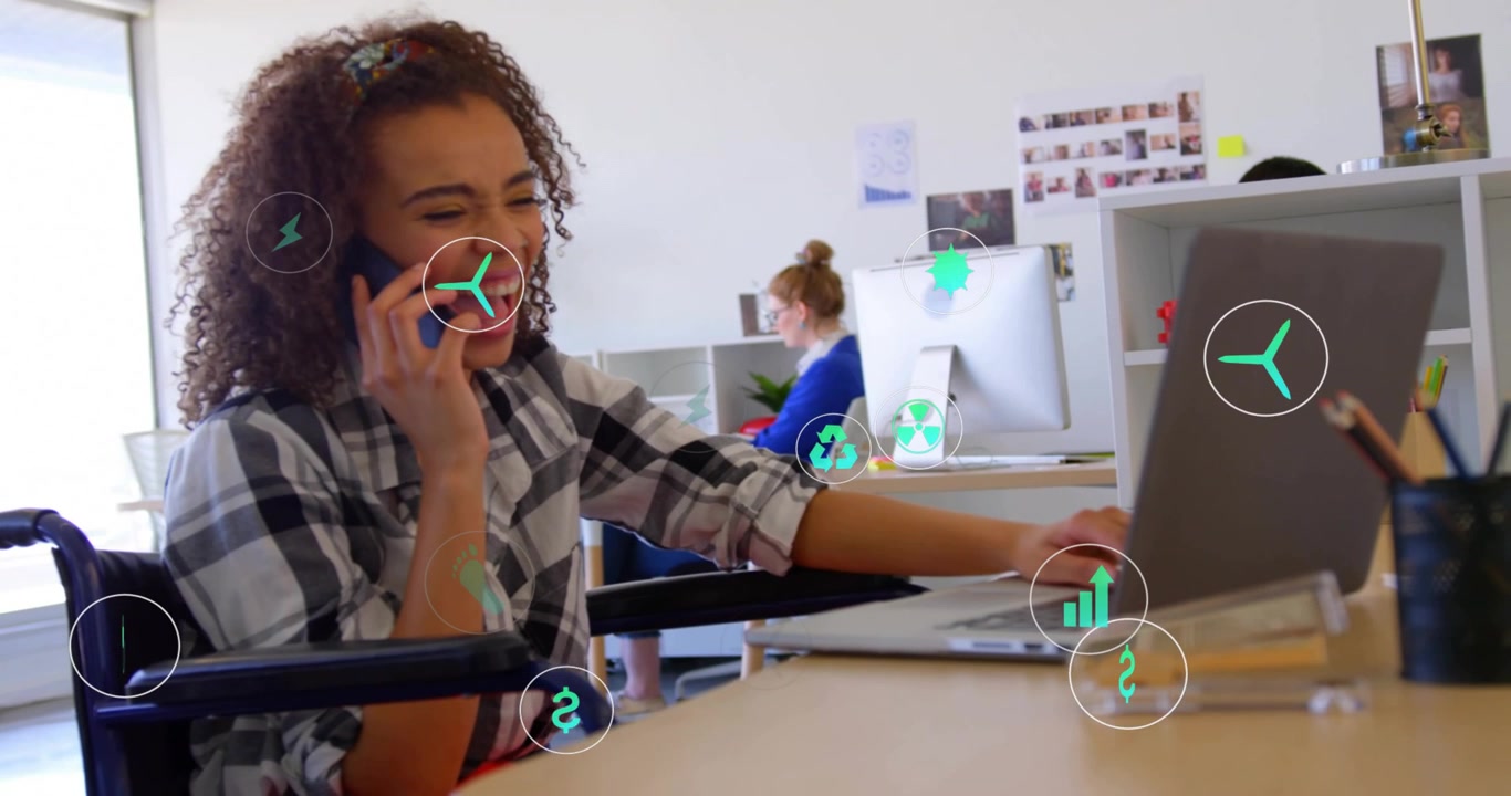 Business manager using laptop while on phone as green icons rising around desk illustrating savings