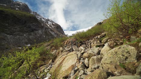 a part of the hike to the buarbreen glacier. ropes and supports hang on the stones to assist hikers. scarce vegetation pops here and there. the mass of the glacier is seen in the background