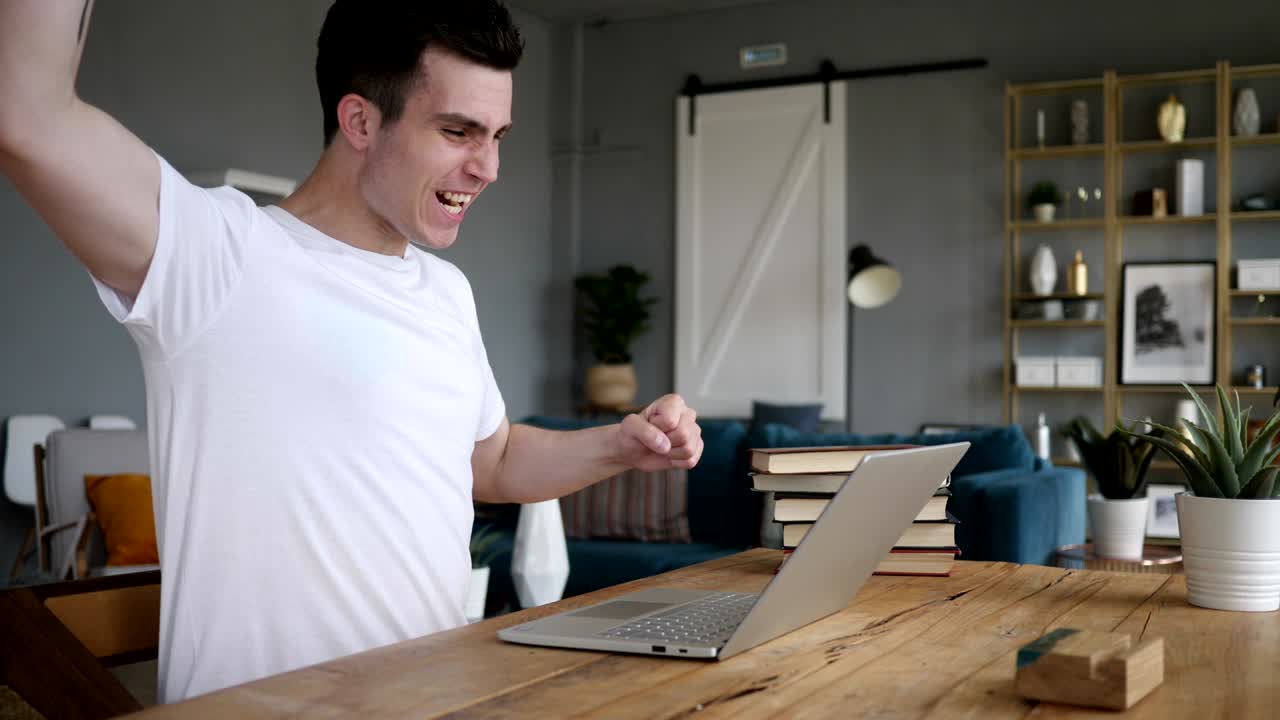 Homem entusiasmado celebrando sucesso, trabalhando no notebook