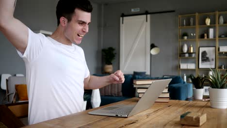 excited man celebrating success, working on laptop