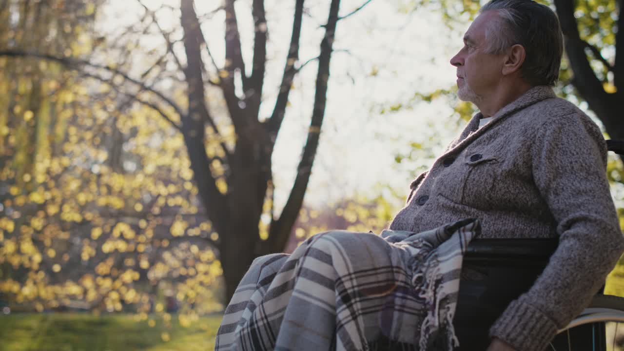 Senior man in a wheelchair on the move in park during the autumn