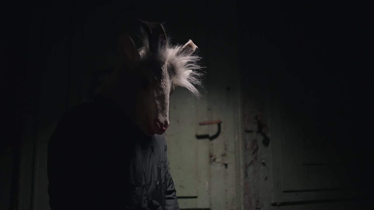 Person Wearing a Goat Mask in a Dark Room