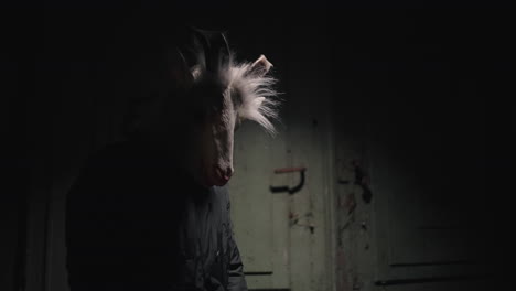 person wearing a goat mask in a dark room