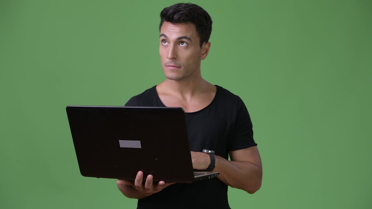 joven y guapo hombre hispano contra un fondo verde