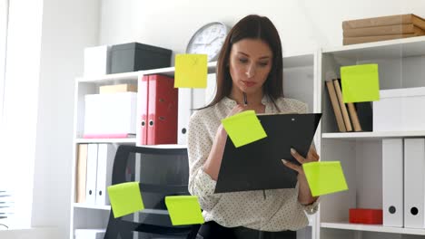 businesswoman making notes in documents standing near glass wall