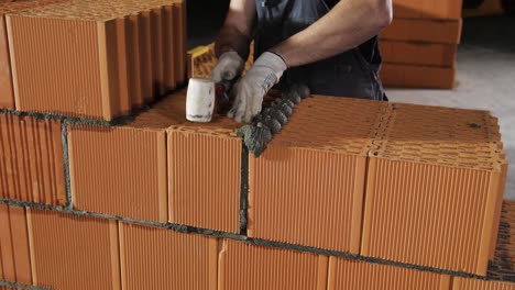 bricklayer applying mortar to bricks